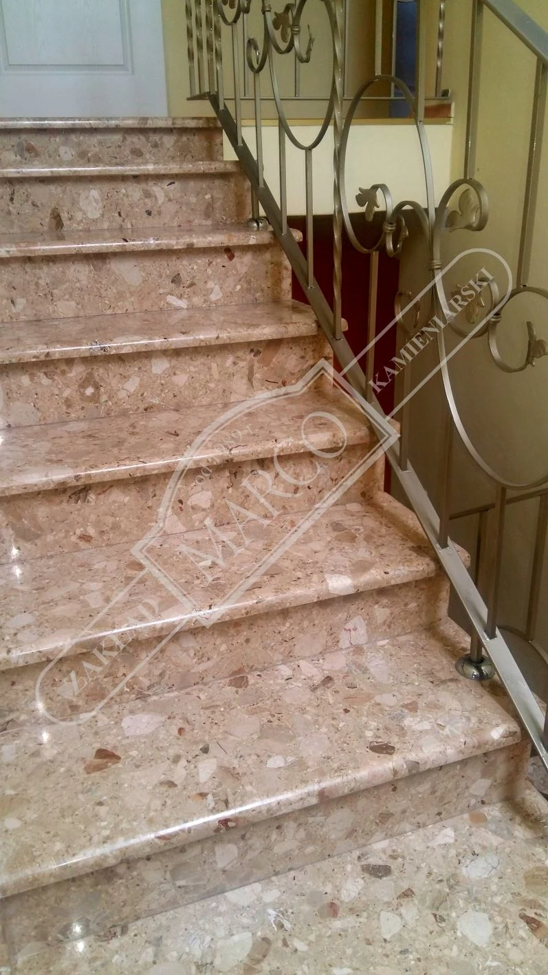 Schody z jasnego kamienia z metalową balustradą